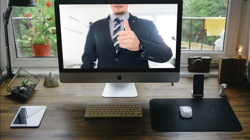 A desktop with a computer monitor featuring a man in a business suit.