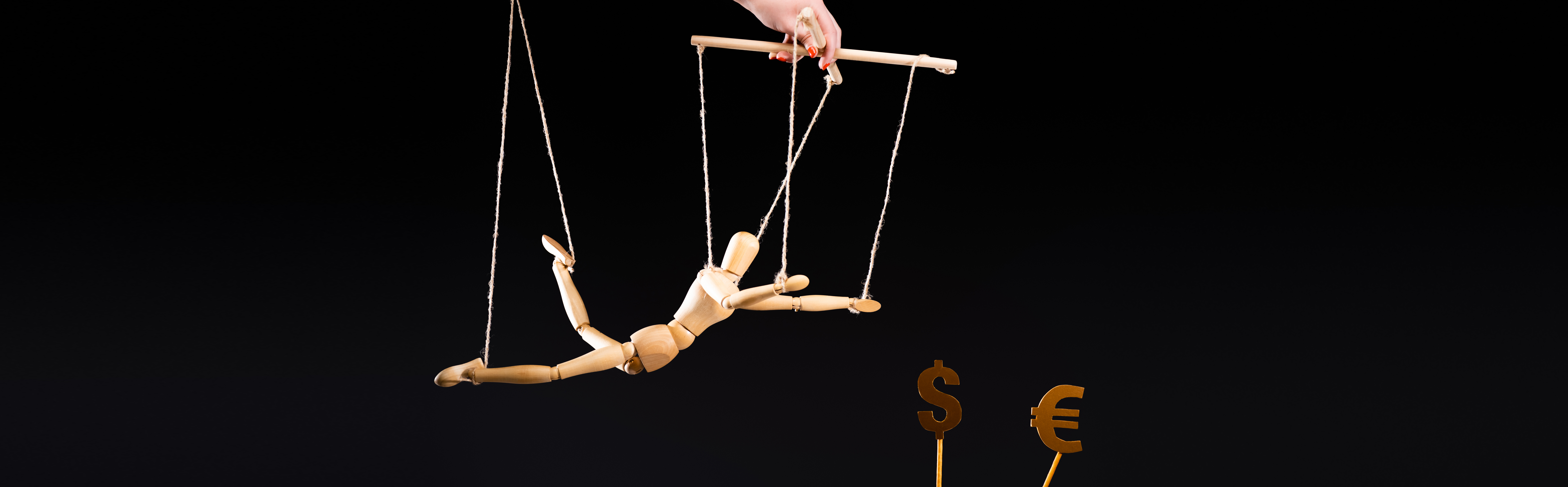 a hand dangles a marionette that reaches toward dollar signs